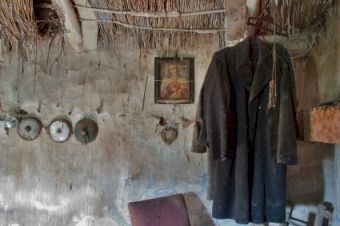 A view of an abandoned cottage in County Clare, with momentos on the crumbling wall and a dusty shirt hanging from a nail.