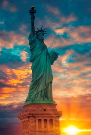 Statue of Liberty against a pink, yellow and blue dawn.